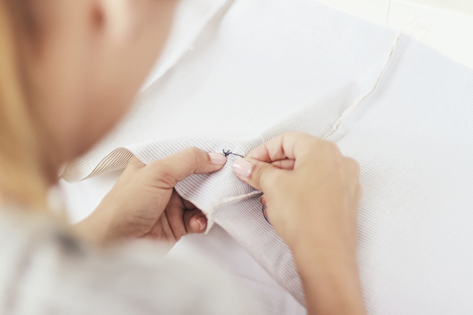 Ręka haftująca delikatny wzór na lnianej tkaninie